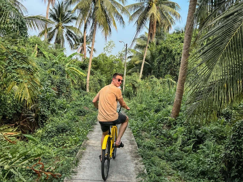 Mann fährt mit Rad durch Palmenlandschaft