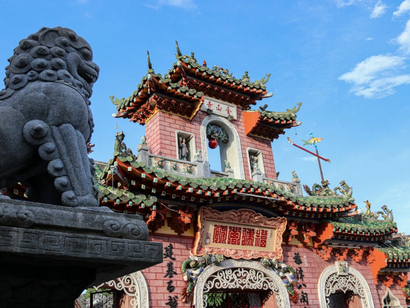 Ein traditioneller asiatischer Tempel mit detailreicher Architektur und einer steinernen Löwenstatue.