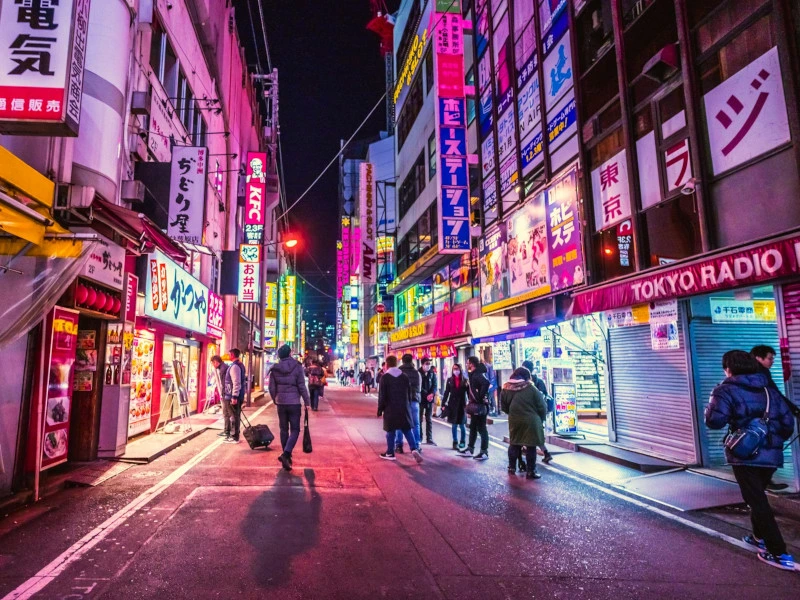 Eine belebte Straßenansicht in Tokyio, Asien, beleuchtet von Neonlichtern bei Nacht