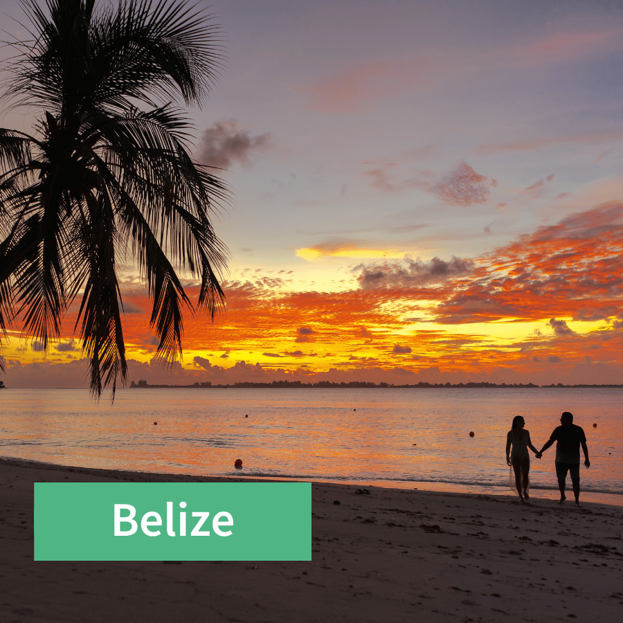 Paar steht händchenhaltend am Strand beim Sonnenuntergang