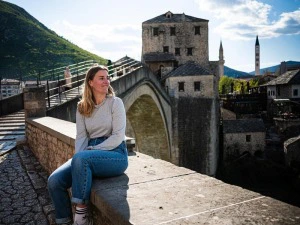 Reisende in Mostar auf Steinmauer sitzend