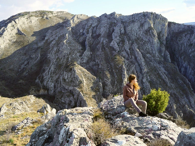 Frau sitzt vor Bergen