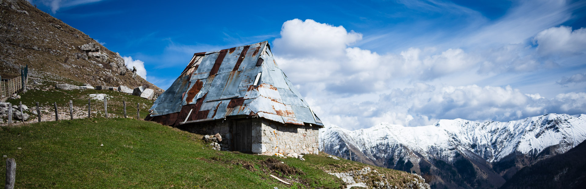 Hütten in den Bergen mit Wolken und schneebedeckten Gipfeln