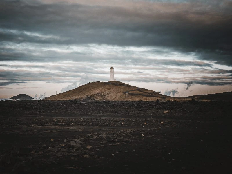 Leuchtturm hinter einer Vulkanlandschaft in Island