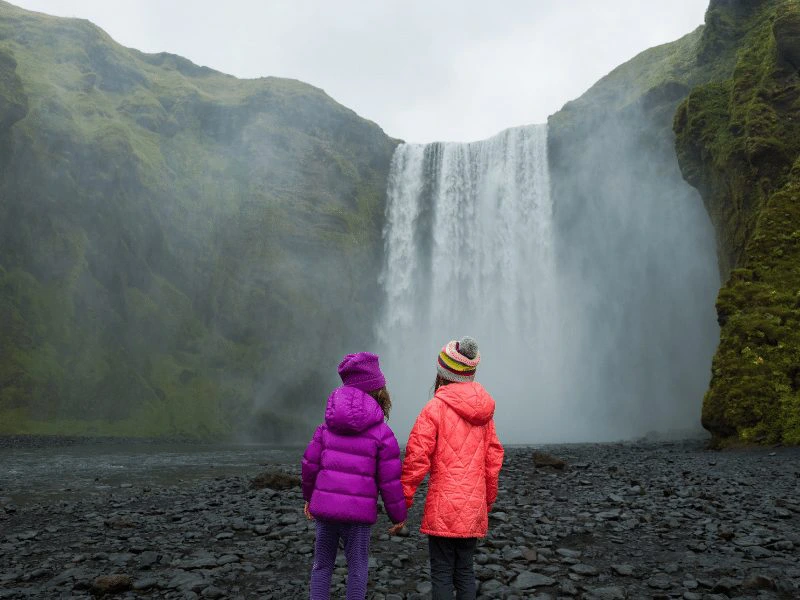 Kinder vor riesigem Wasserfall in Island
