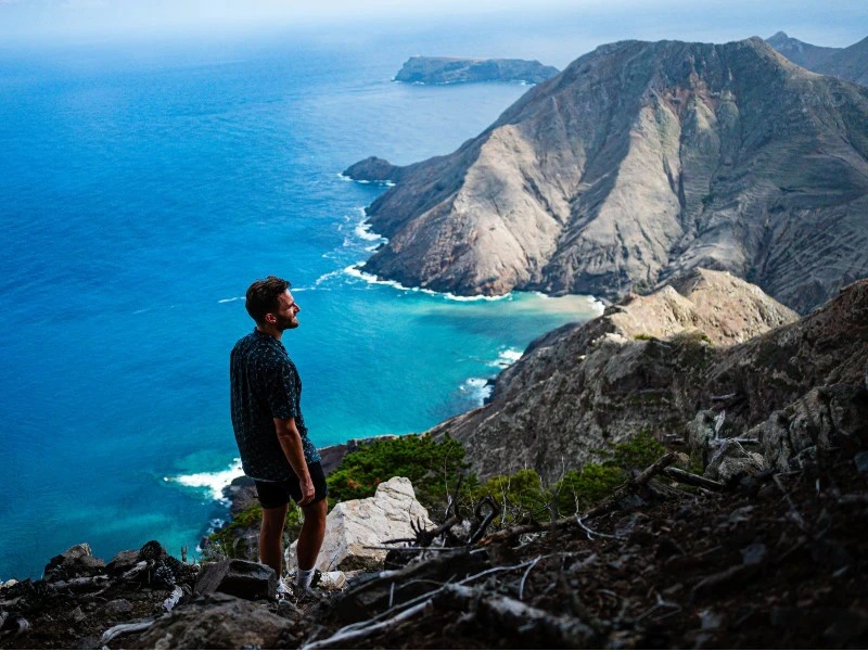 Mann steht auf einer klippe am Meer umgeben von Natur