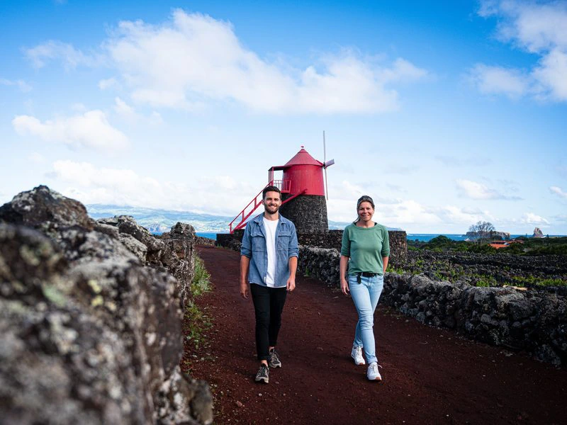 Paar läuft mit Leuchtturm im Hintergrund