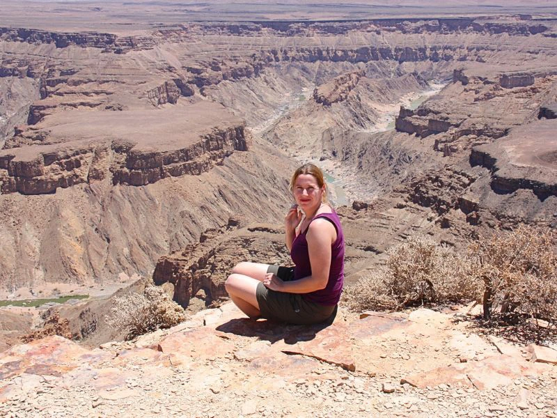 Frau sitzt am Rande des Fish River Canyon