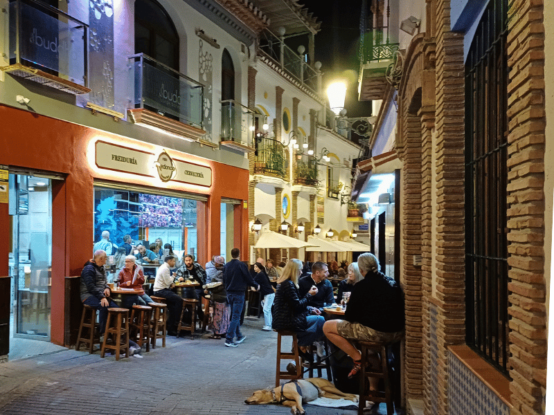 Volle Tische vor Bars in einer kleinen Gasse in Nerja, Andalusien
