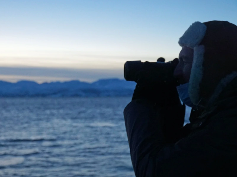 Reisender mit Fernglas auf Walsafari in Norwegisch Lappland