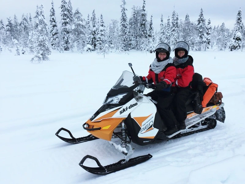 Reisende bei Schneemobiltour in Lappland