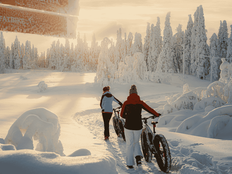Reisende mit Fatbikes im Schnee in Ukkohalla, Lappland