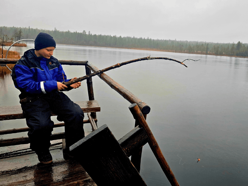 Junge angelt mit Ast im See