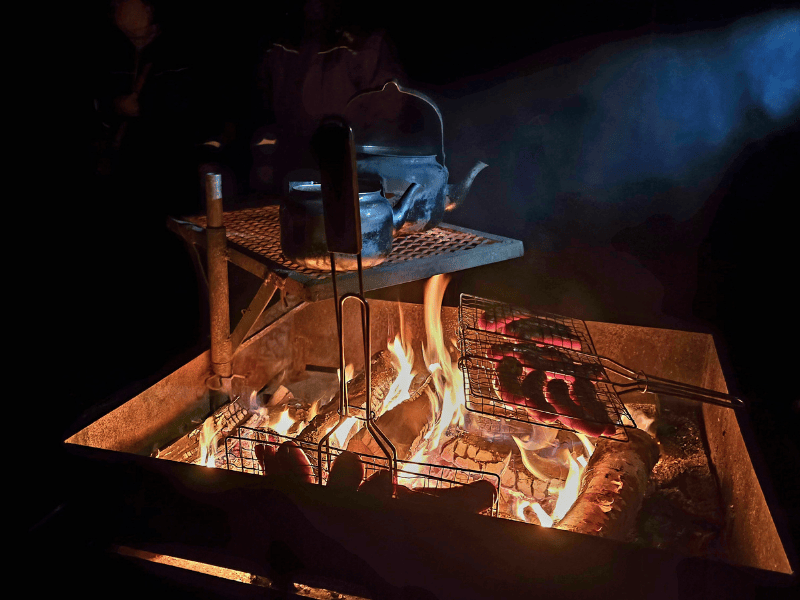 Würstchen grillen über einem Lagerfeuer