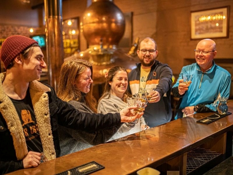 Besucher stoßen mit Whisky bei der Brennereitour an