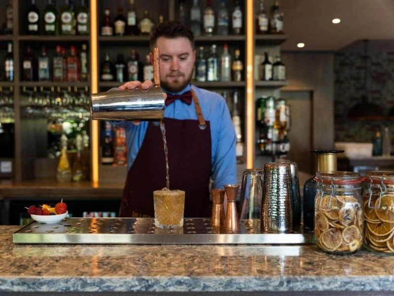 Barkeeper schenkt einen Cocktail in der Hotelbar aus.