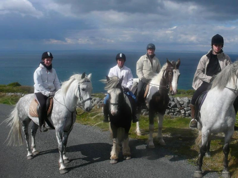 Gruppe von Reisenden auf ihren Pferden mit Meer im Hintergrund.