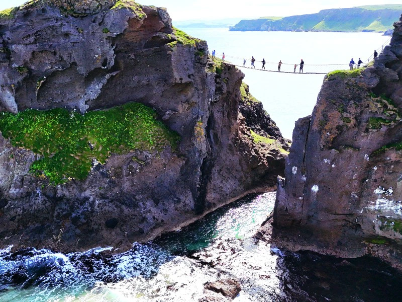 Blick auf Felsen, Wellen und Hängebrücke