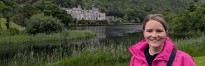Frau vor Kylemore Abbey, umgeben von grüner Vegetation
