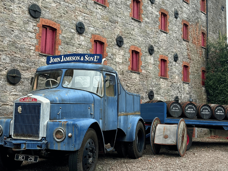 Altes Auto mit Whiskeyfässern auf dem Anhänger vor Gebäude mit roten Fensterläden