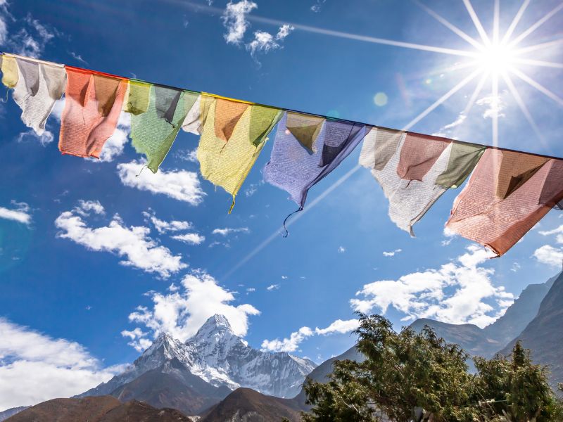 Gebetsflaggen in der Sonne vor einer Bergkulisse in Nepal