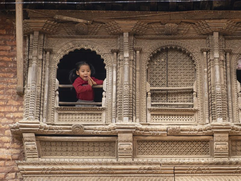 Kleines Mädchen schaut aus Fenster in einem traditionellen Haus in Nepal