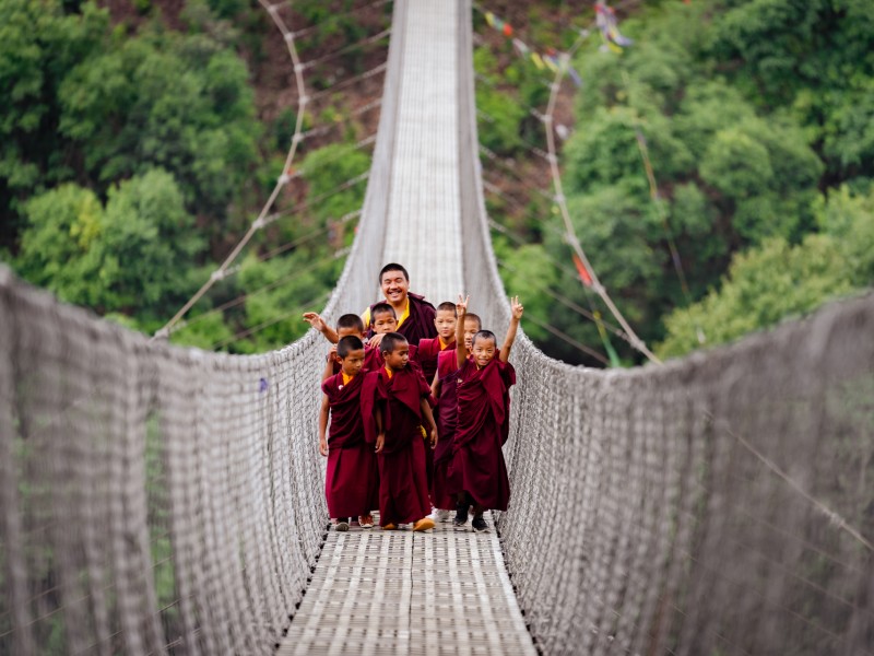 Mönche auf einer Hängebrücke zum Neydo Kloster in Nepal