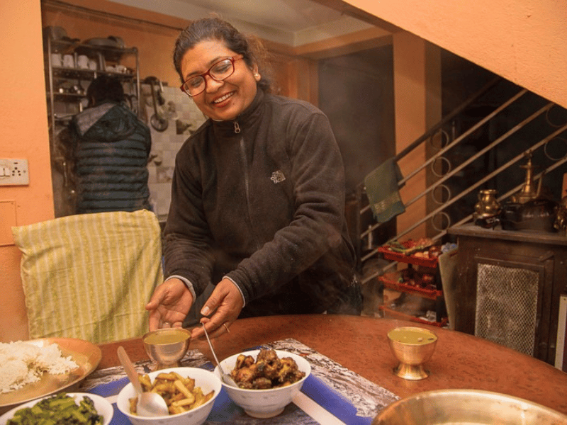 Gastgeberin im Homestay in Nepal serviert traditionelles Essen