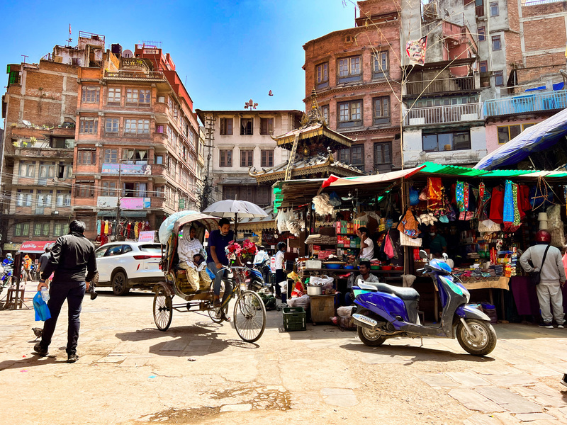 Straßenszene mit Rikscha und Marktstand in Kathmandu