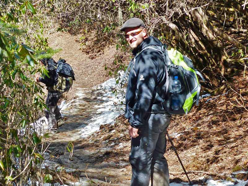 Wanderer auf einem Waldweg mit Schneeresten in Bhutan