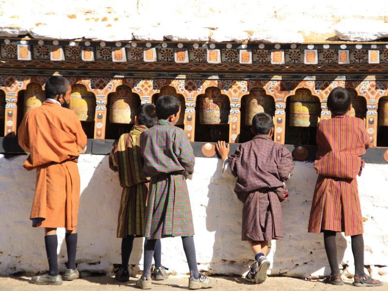 Einheimische Jungs an Gebetsmühlen in Bhutan
