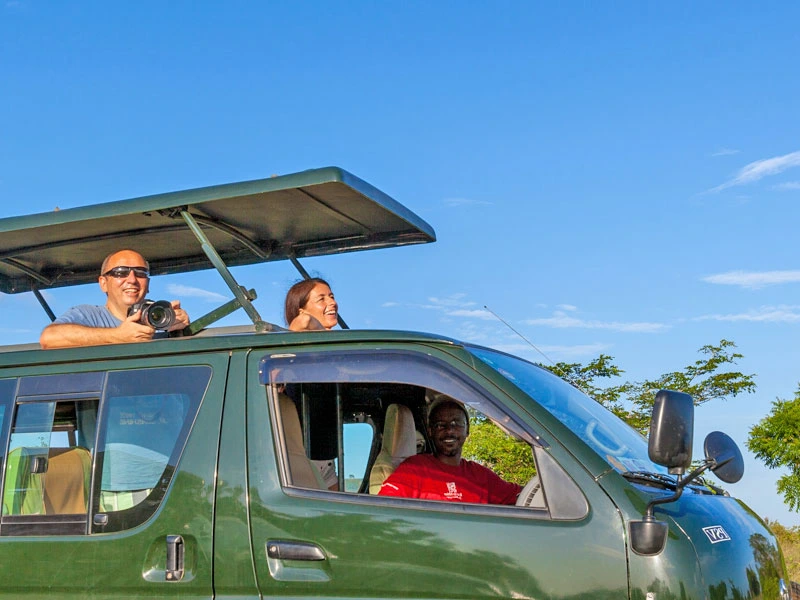 Reisende schauen aus der offenen Dachluke im Minivan in Tansania