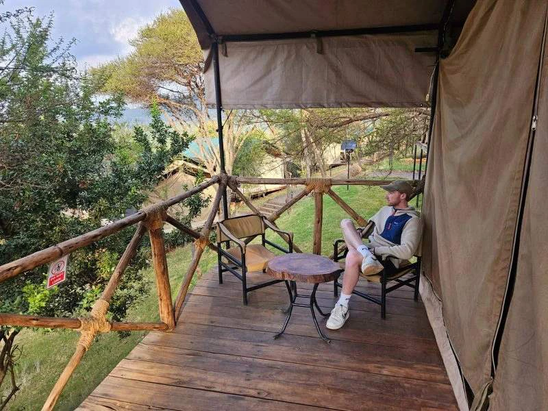 Mann sitz auf einem Stuhl auf der Veranda eines Zeltcampes in der Natur
