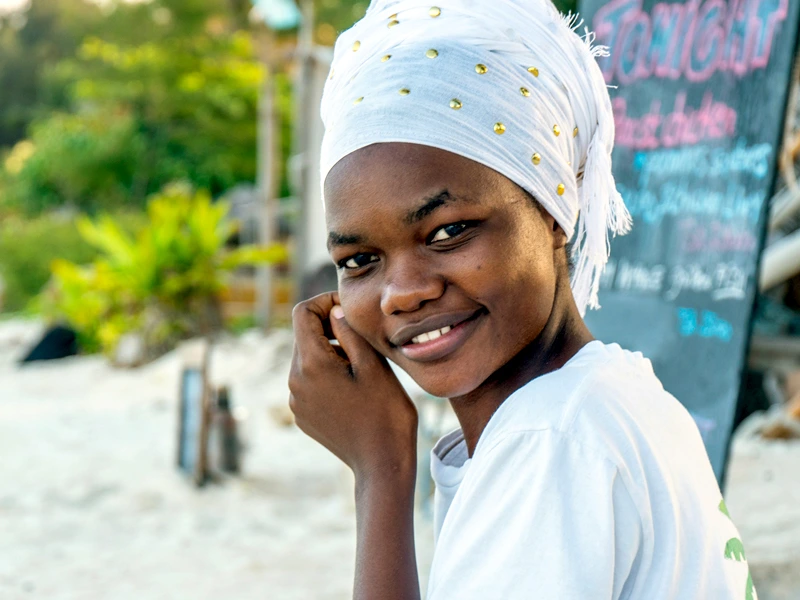 Lachende tansanische junge Frau am Strand