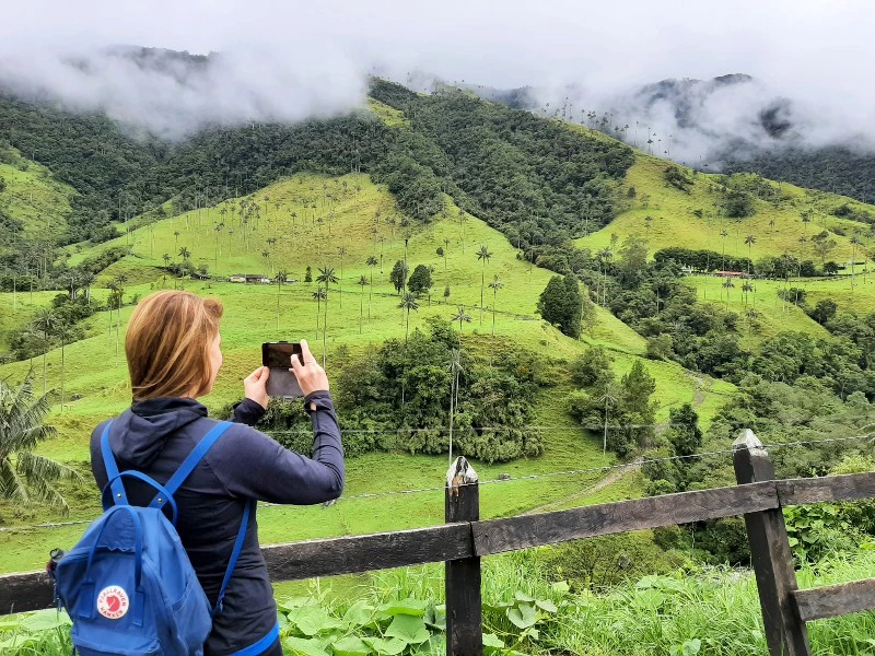 Frau, die ein Foto von den grünen Bergen im Kaffeedreieck in Salento, Kolumbien, macht, umgeben von der atemberaubenden Natur