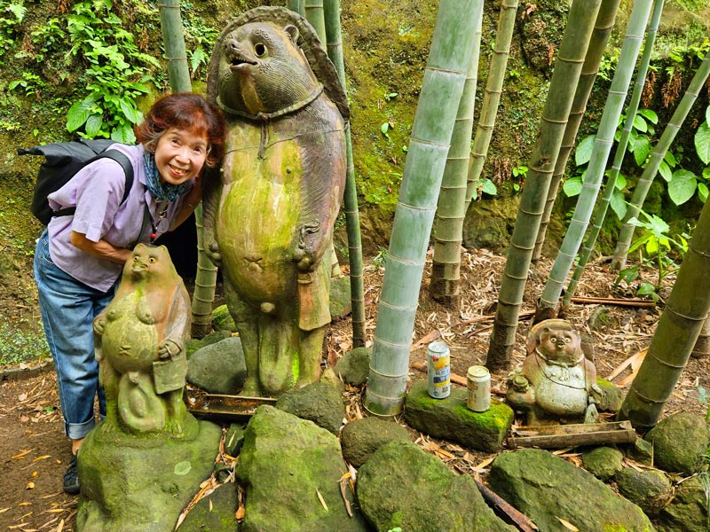Guide an Steinstatuen zwischen Bambuspflanzen in Kamakura