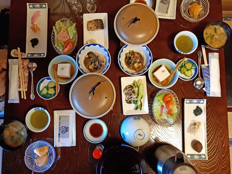 Gedeckter Tisch mit vielen kleinen, typisch japanischen Speisen in einem Ryokan in Yunohira