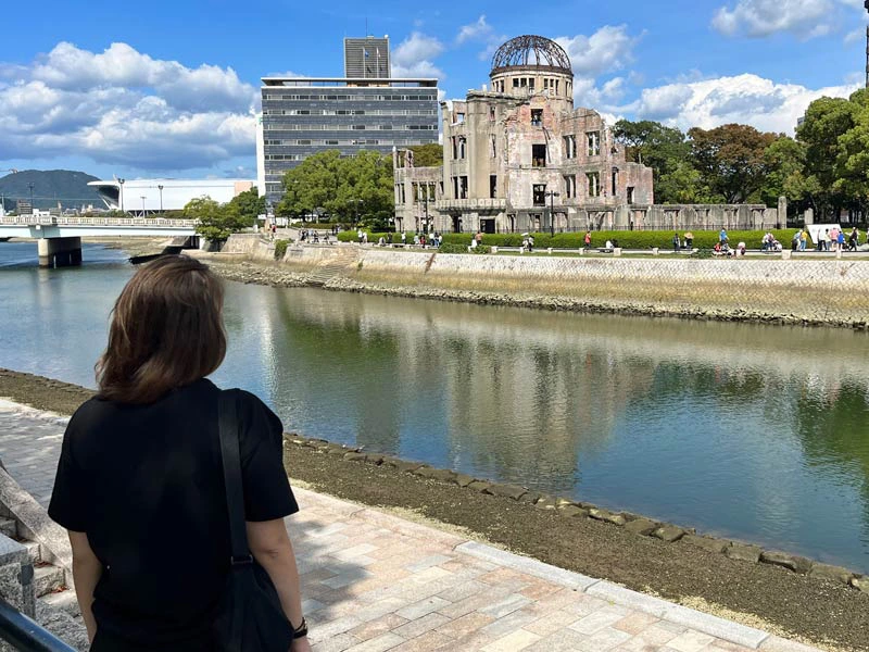 Frau am Ufer gegenüber des Atombombendoms in Hiroshima