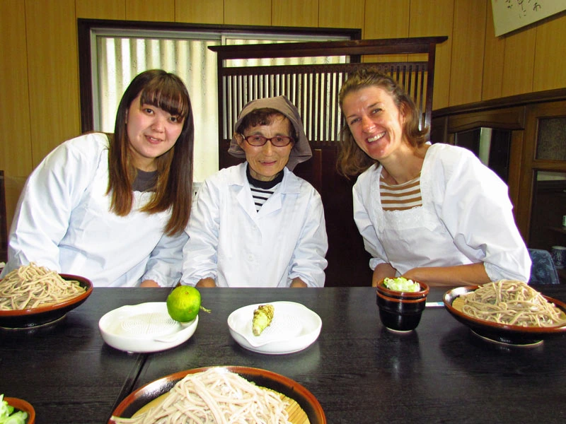 Reisende sitzen zusammen mit der Gastgeberin im Homestay beim Sobanudelnessen in Gotemba am Mount Fuji in Japan