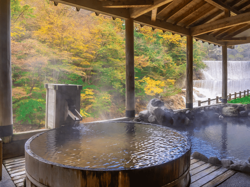 Onsen auf der Terasse am Fluss während der Herbstfärbung