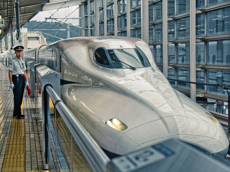 Schaffner am Bahnhof während ein Shinkansen einfährt in Japan