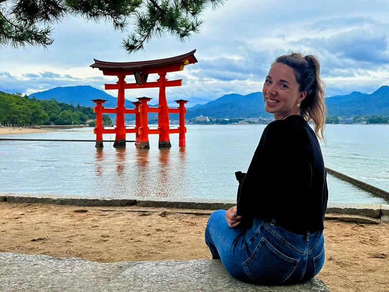 Reisende vor großem Torii im Wasser am Strand von Miyajima in Japan