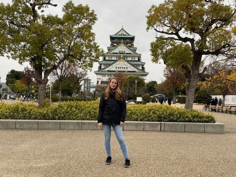 Frau steht vor der Burg "Osaka Castle"