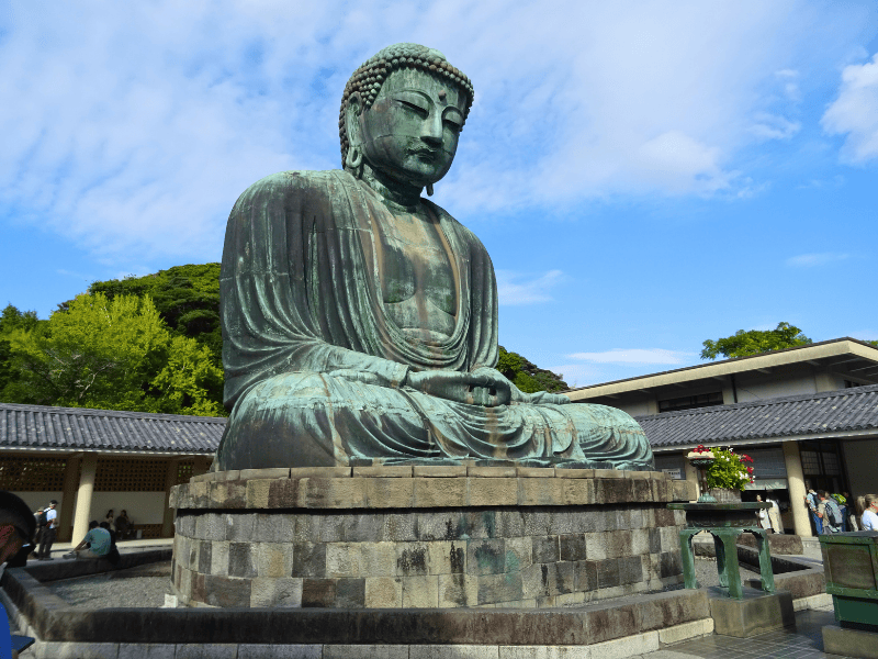 Großer Bhudda auf Steinsockel vor blauem Himmel