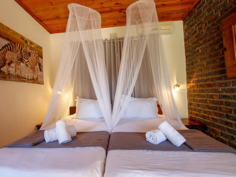 Schlafzimmer mit Moskitonetz und Kingsizebett im Hluhluwe Wildpark