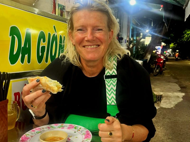 Frau isst an einer Garküche in Vietnam