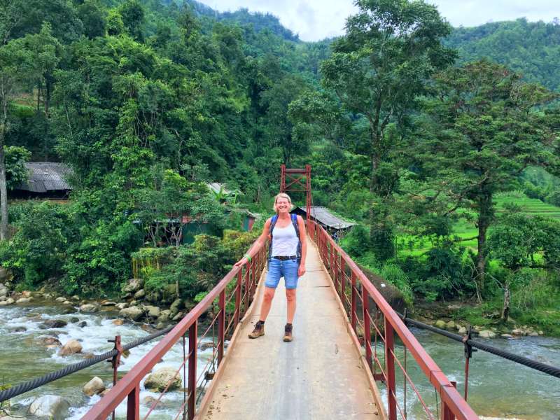 Touristin beim Wandern auf einer Brücke zu einem lokalen Dorf bei Mu Cang Chai, Vietnam