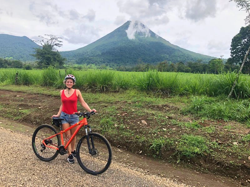 Frau mit Fahrrad vor dem Vulkan Arenal in Costa Rica