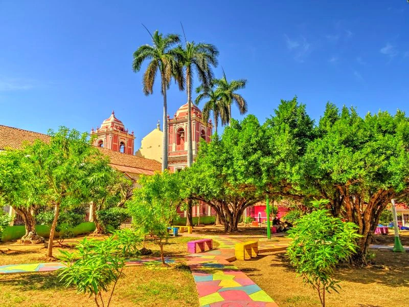 Park mit kolonialer Kirche im Hintergrund in Leon, Nicaragua