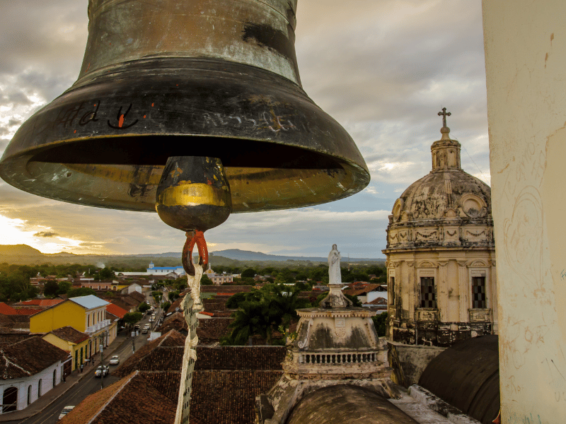 Ein lebhafter Park in Granada, Nicaragua, mit Palmen, bunten Wegen und der beeindruckenden Fassade einer kolonialen Kirche – ein Muss unter den Nicaragua Sehenswürdigkeiten.